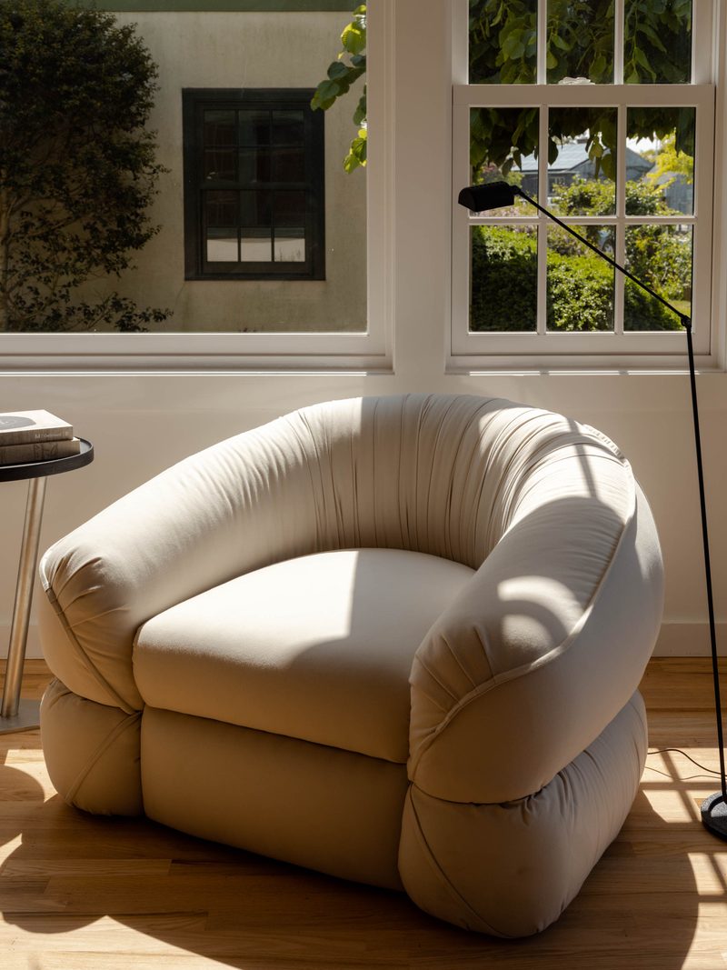 Rounded armchair and timber stool by a window