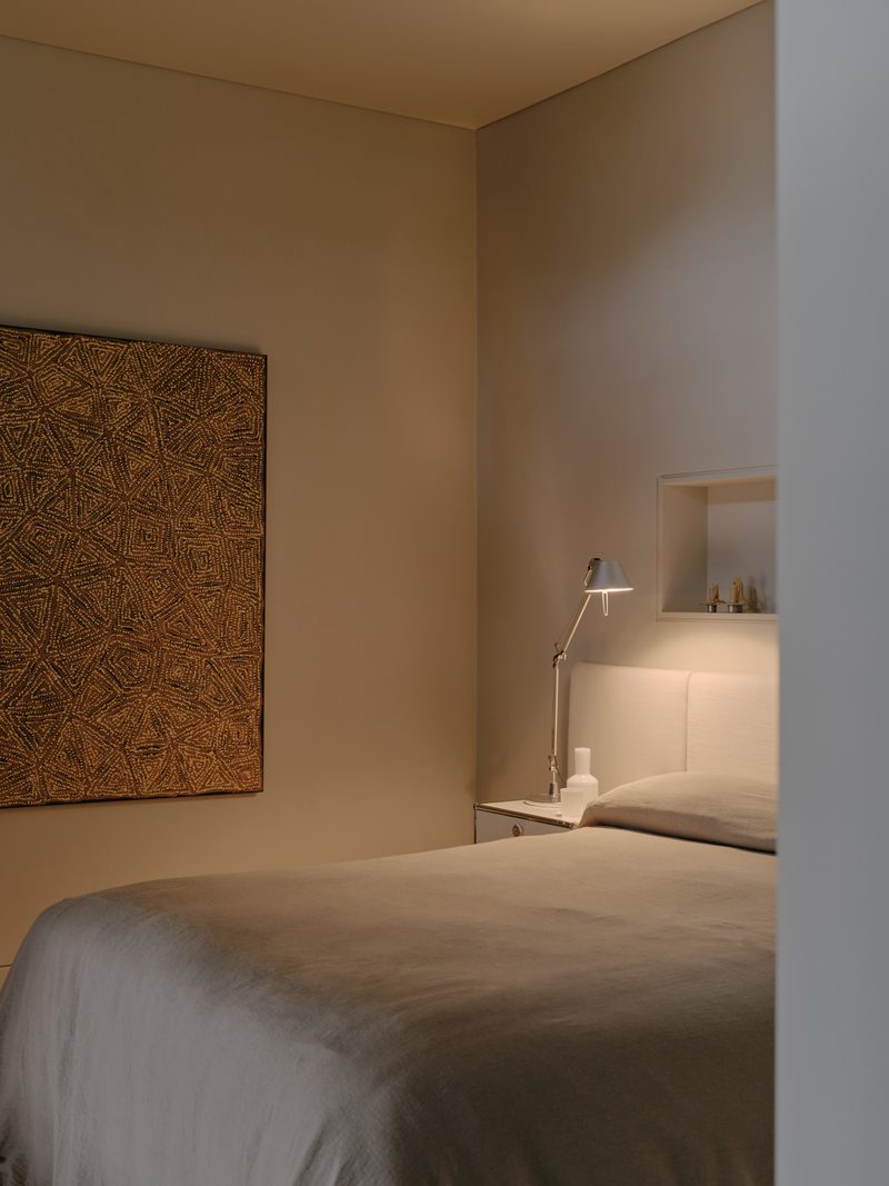 Bedroom with a framed textile artwork and wall lamp